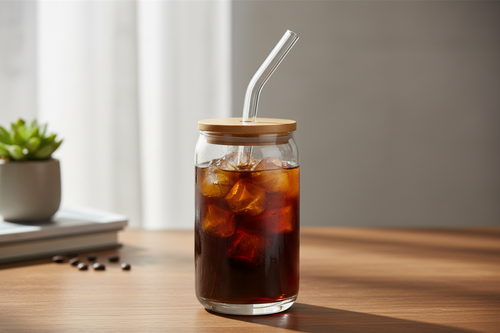 Clear glass tumbler with bamboo lid and glass straw holding an iced drink